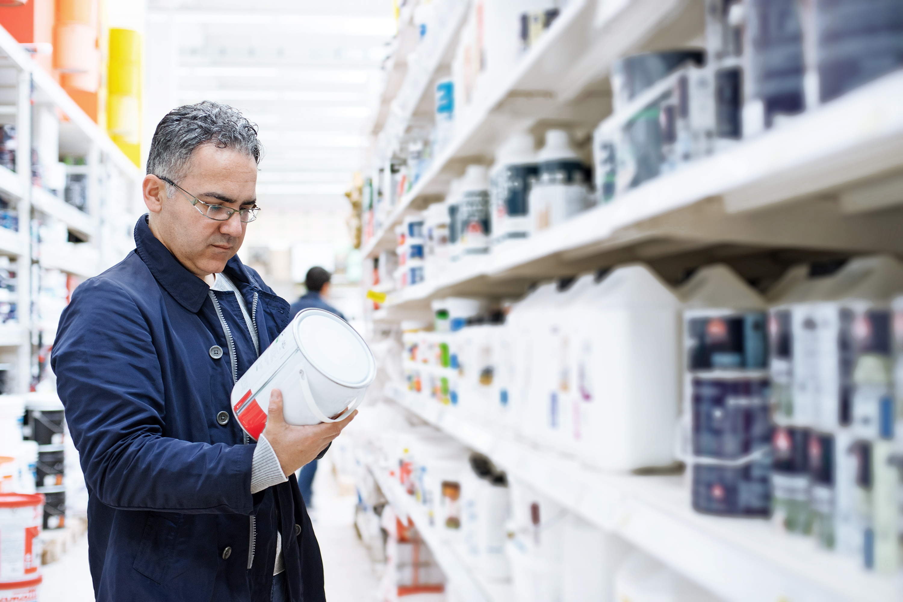 man looking at paint can in store